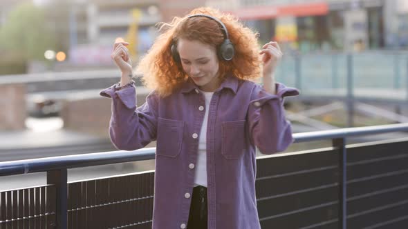 Woman dancing to music from headphones in the city