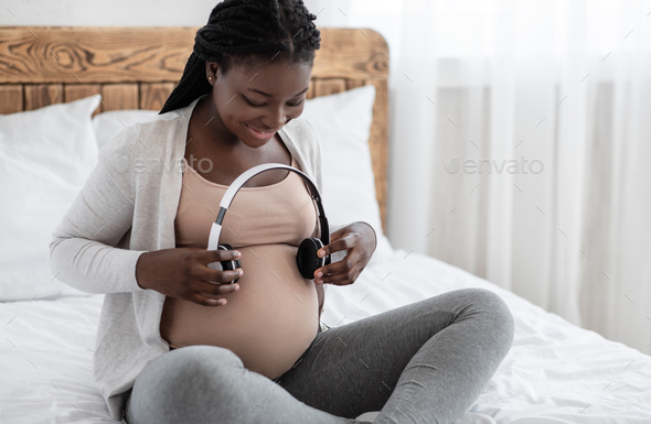 Pregnant woman holding headphones on her belly. Stock Photo by  ©stock.sokolov.com.ua 323986988