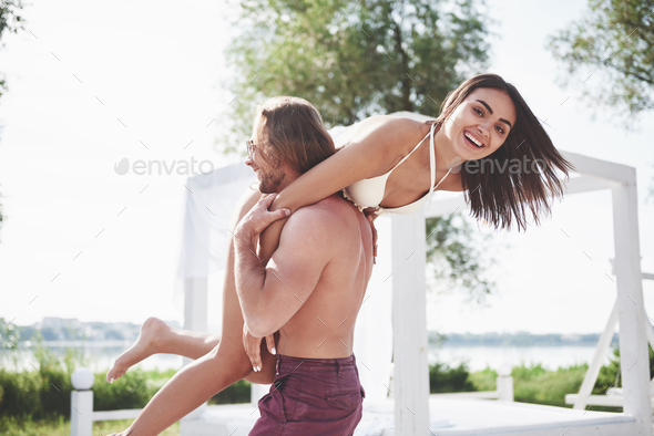Beautiful young people are fond of it. A man holds a woman on his shoulders, they are playful and