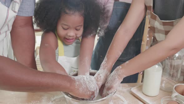 Close up of African American Mom, dad, and two daughters helping thresh dough together