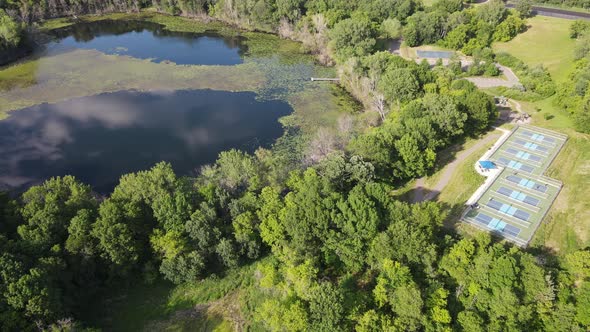 Aerial view of park with small water body and diverse vegetation with park surrounding.