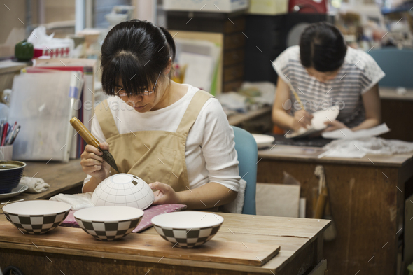 Woman working in a Japanese porcelain workshop, painting geometric pattern