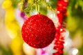 Glowing Red Christmas Ball and Colorful Shining Tinsel Hanging on Branch of Pine Tree - PhotoDune Item for Sale