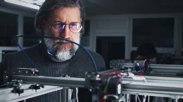 Mature Designer Watching Work of 3D Printer alt