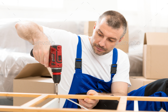 Furniture Assembler Assembling Cabinet Working Using Electric Drill Indoors