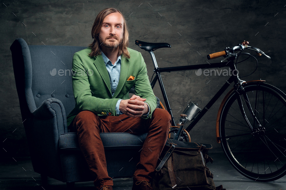 A man sits on a chair with the bike on a background. Stock Photo by fxquadro