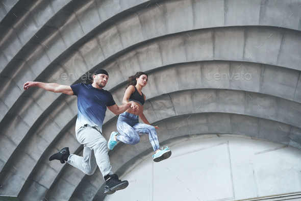 Young happy sports couple in the city street, performing parkour