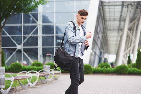 Young handsome man with a bag on his shoulder in a hurry to the airport