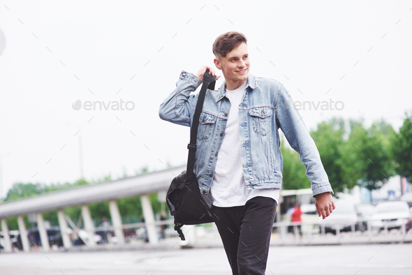 Young handsome man with a bag on his shoulder in a hurry to the airport