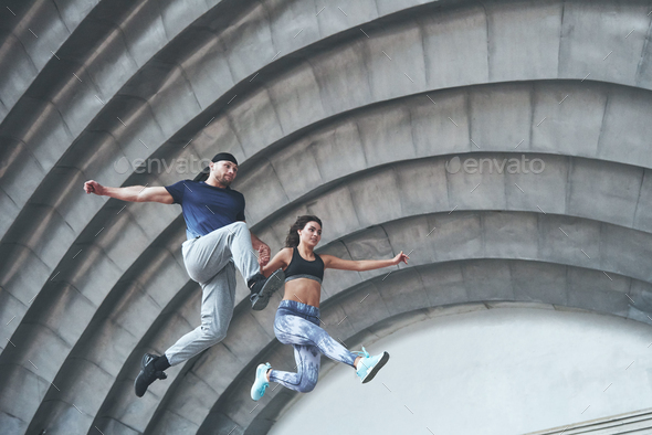 Young happy sports couple in the city street, performing parkour