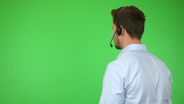 A Young Handsome Call Center Agent Talks To a Caller with His Back To the Camera - Green Screen alt