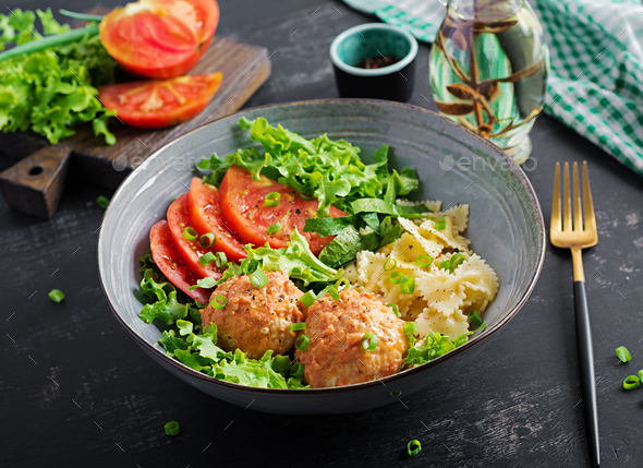 Italian pasta. Farfalle with meatballs and salad on dark background. Dinner. Slow food concept - Stock Photo - Images