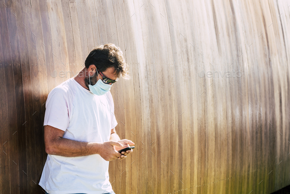 Adult man with medical mask type on the phone and read news in outdoor