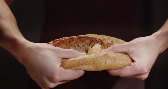 A Man Tears A Loaf Of Freshly Baked Bread In Half. The Texture Of Buckwheat Bread