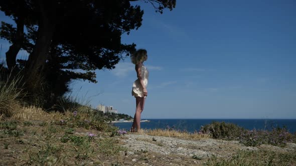 Slender Girl Looks at the Sea From the Shade of a Tree