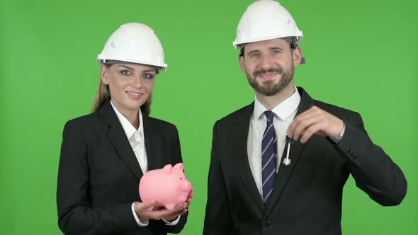 Engineers Posing with Piggy Bank and Construction Equipment Against Chroma Key alt