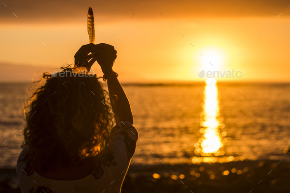 Freedom and meditation concept image with woman taking a feather like life during a sunset