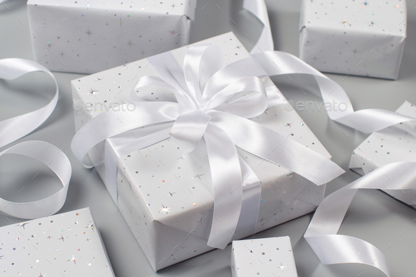Wrapped grey Gift boxes with white ribbon on grey Stock Photo by katrinshine