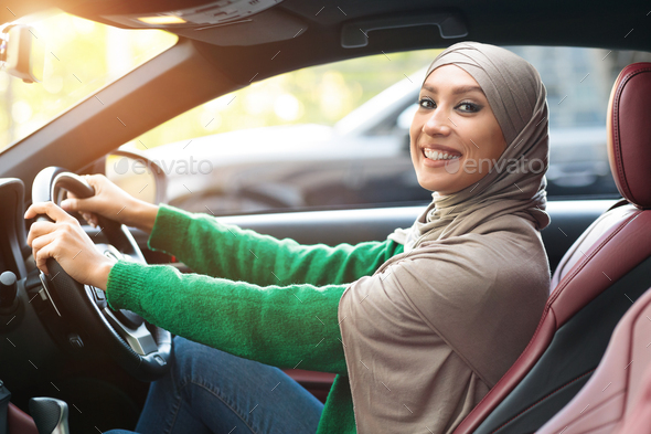 Positive smiling muslim woman driving her new car