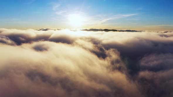 Sun Shining Brightly Above White Fluffy Clouds at Sunrise alt