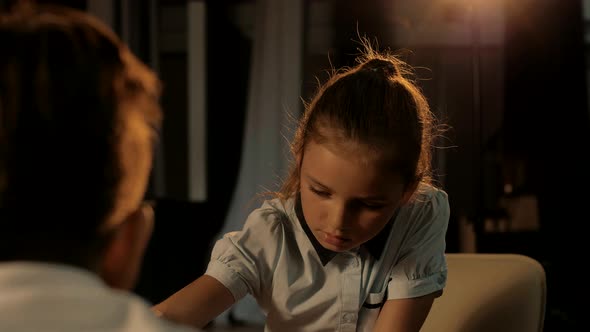 A young cute girl makes a move in a chess board.