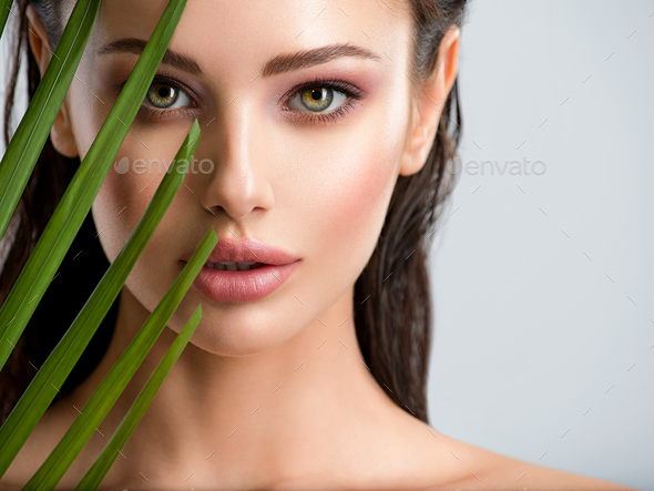 Young beautiful woman with healthy skin of face and palm leaves. - Stock Photo - Images