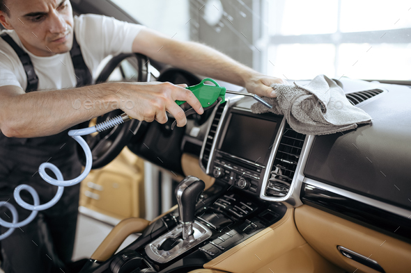 Worker with air gun cleans car air duct grating