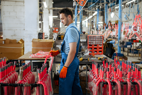 Bicycle factory, worker holds pink kid\'s bike fork