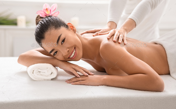 Wellness Concept. Beautiful asian lady enjoying back massage in spa center