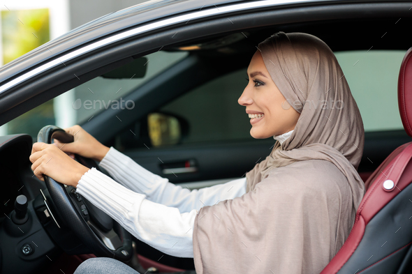 Cheerful smiling muslim woman driving alone her new car