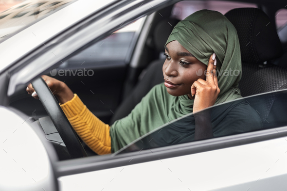 Bored Black Muslim Woman In Hijab Driving Car In Traffic Jam