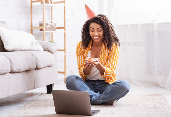Happy black lady in party hat celebrating birthday online