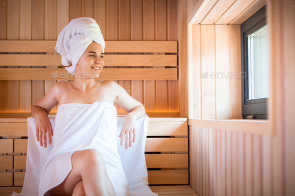 Girls relaxing in the sauna in white towels. Stock Photo by