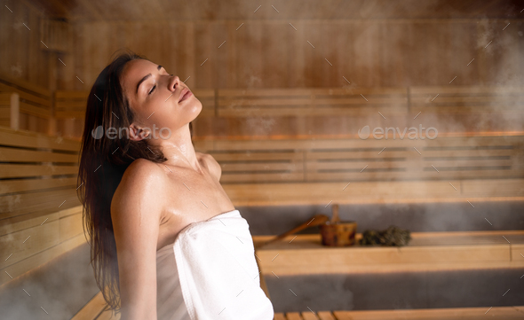 Girls relaxing in the sauna in white towels. Stock Photo by