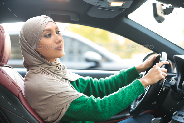 Experienced muslim woman test driving new car in urban city
