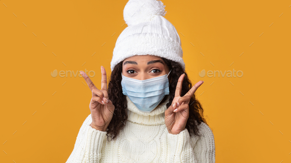 Portrait of black woman in medical mask showing victory sign