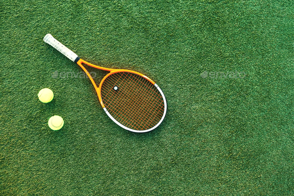 Tennis balls and racket on the grass court Stock Photo