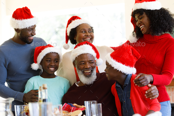 Multi generation african american family smiling and wearing santa hats