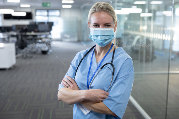 Portrait of confident Caucasian female medical professional wearing face mask and scrubs. Social distancing and hygiene in the workplace during Coronavirus Covid 19 pandemic.