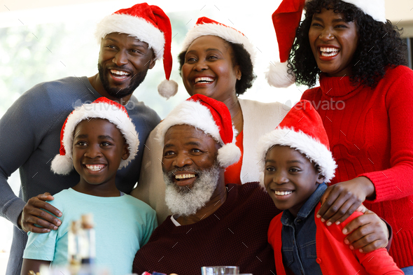 Multi generation african american family posing, smiling and wearing santa hats. quality family time christmas celebration.