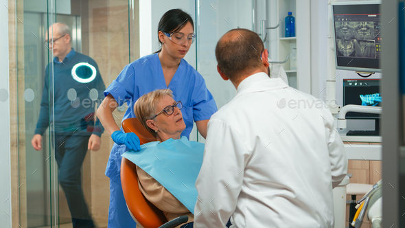 Nurse putting dental bib to old woman