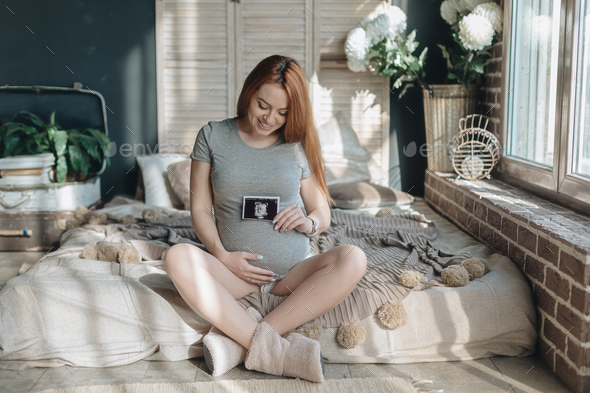 Pregnant woman holding ultrasound scan of baby - Stock Photo - Images