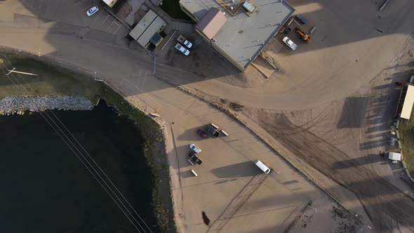 Slowly lowering aerial shot with gimbal tilted 90 degrees down over a small parking lot next to indu alt