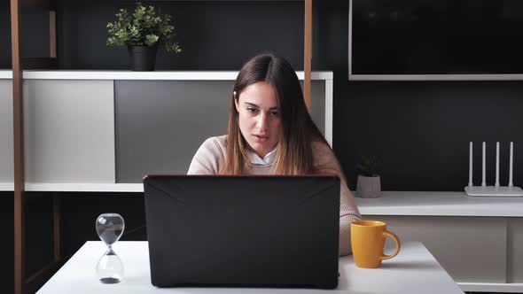 Euphoric Young Woman Winner Looks at Laptop Celebrates Online Success Sits at Modern Office alt