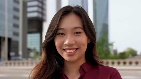 Young asian business woman smiling on camera with tower in the background