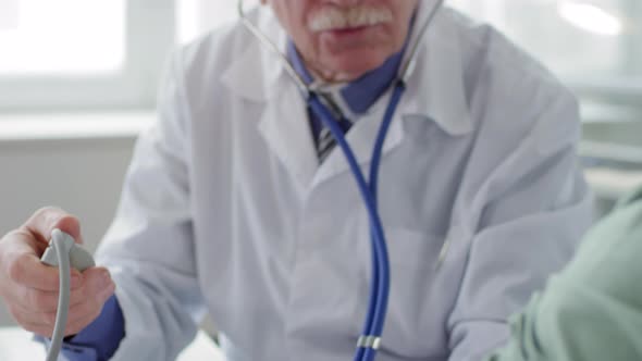 Senior Physician Checking Up Health of Young Man alt