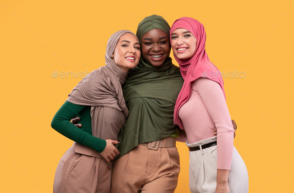 Three Beautiful Islamic Women In Hijab Posing Over Yellow Background