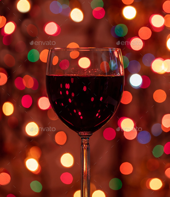 Red wine glass against christmas lights bokeh background Stock Photo by  rawf8