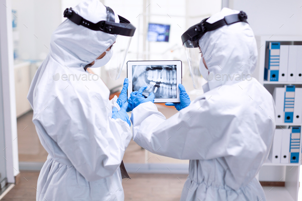 Dentistiry team in ppe suit holding tablet with teeth digital xray