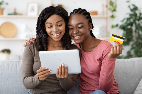Happy black ladies shopping online, using digital tablet at home